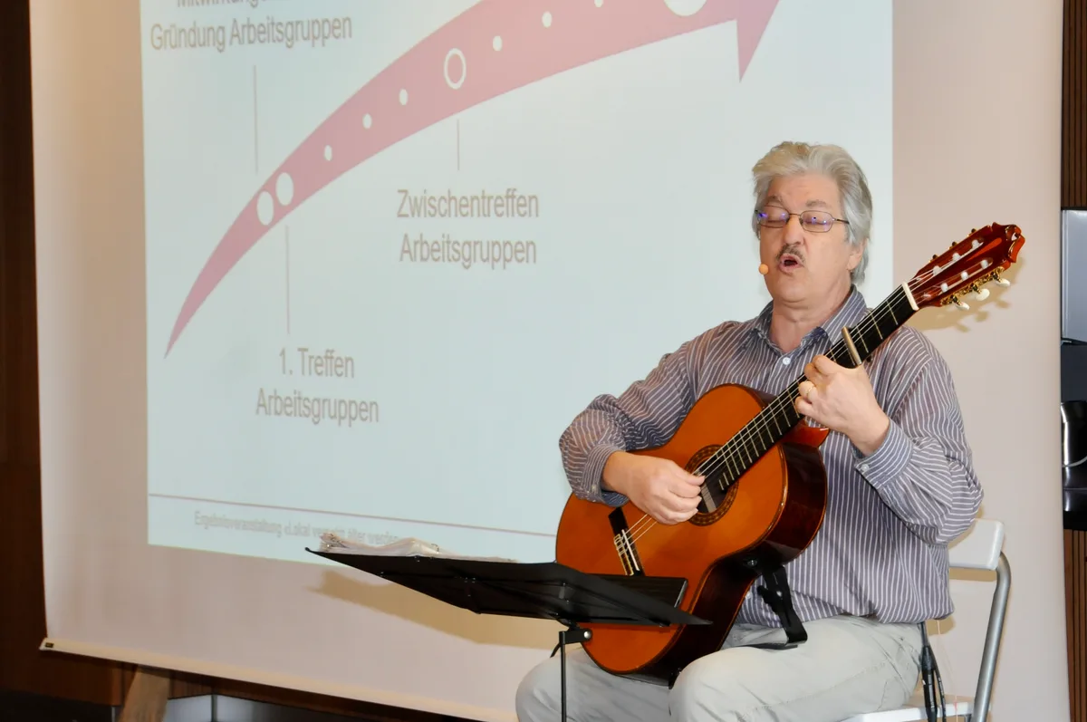 Man sieht einen singenden Mann mit einer Gitarre.